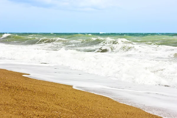 Marea furtunoasa si cerul albastru, spuma alba de mare pe o plaja galbena cu nisip . — Fotografie, imagine de stoc