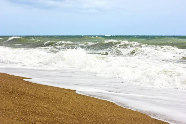 Mer orageuse et ciel bleu, mousse de mer blanche sur une plage de sable jaune . — Photo