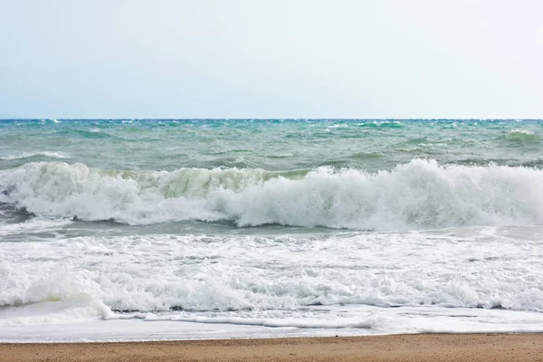 Mer orageuse et ciel bleu, mousse de mer blanche sur une plage de sable jaune . — Photo