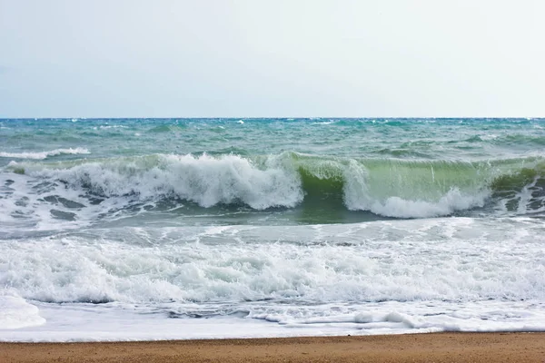 Mer orageuse et ciel bleu, mousse de mer blanche sur une plage de sable jaune . — Photo