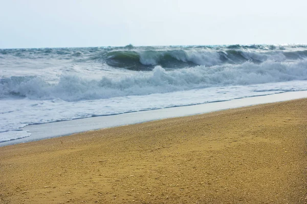 Marea furtunoasa si cerul albastru, spuma alba de mare pe o plaja galbena cu nisip . — Fotografie, imagine de stoc