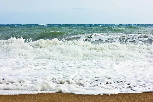 Marea furtunoasa si cerul albastru, spuma alba de mare pe o plaja galbena cu nisip . — Fotografie, imagine de stoc