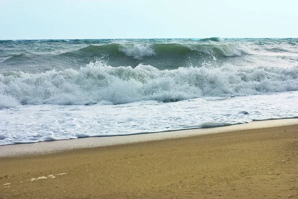 Mer orageuse et ciel bleu, mousse de mer blanche sur une plage de sable jaune . — Photo