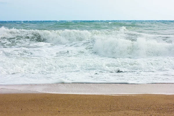 Mare tempestoso e cielo azzurro, schiuma di mare bianca su una spiaggia di sabbia gialla . — Foto stock gratuita