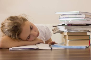 Yorgun kız öğrenci başını masaya oturuyor ve bakar bir 