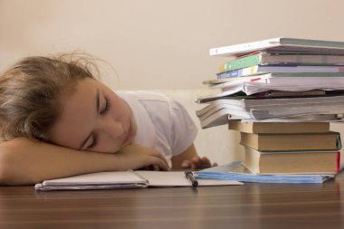 Yorgun kız öğrenci başını masaya oturuyor ve bakar bir 