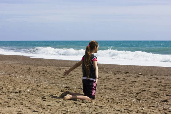 Ung flicka sitter på stranden nära havets blåa — Stockfoto