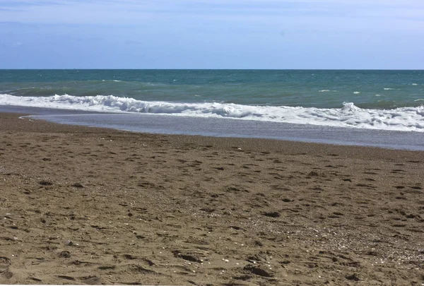 Mar tempestuoso e céu azul, espuma de mar branco em uma praia de areia amarela . — Fotografia de Stock