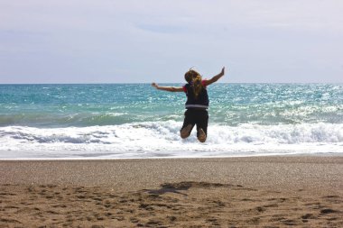 Genç kız çalışır ve mavi denize sıfır plaj atlar