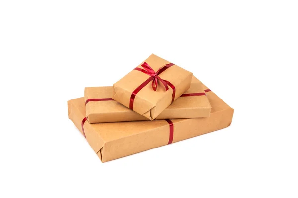 Κουτιά δώρων σε χαρτί περιτυλίγματος χειροτεχνίας με απομονωμένες κόκκινες κορδέλες — Φωτογραφία Αρχείου