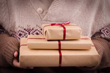 Elinde kırmızı kurdele olan hediye kutuları. El sanatları kağıdında hediyeleri tutuyor.