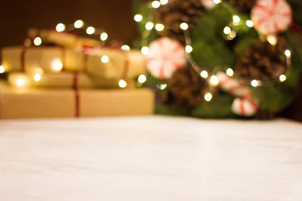 Hediye kutuları ve parlak çelenkli Noel çelengi. Bokeh ile odak olmadan bulanık arkaplan