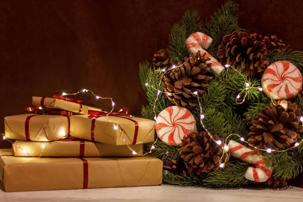 Cajas de regalo y corona de Navidad con una guirnalda luminosa . —  Fotos de Stock