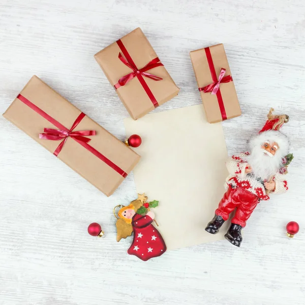 Christmas and New Year background with gift boxes, Santa and sheet of paper on white wooden table — ストック写真