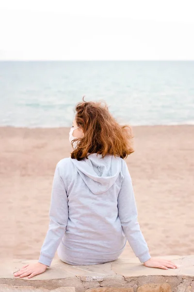 Jovem Adolescente Com Máscara Médica Senta Praia Olha Para Mar — Fotografia de Stock