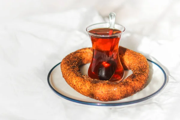 Breakfast in bed. Turkish tea in traditional glass and simit sesame bun