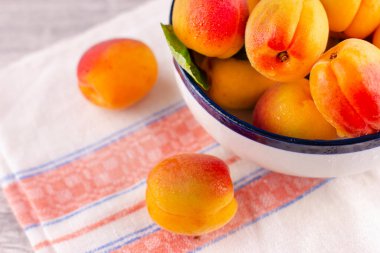 Beyaz ahşap bir masada taze kayısı. Olgun tatlı böğürtlenler su damlacıklarında