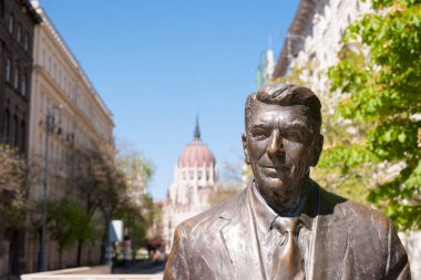 BUDAPEST, HUNGARY - 20 Nisan 2020: Macaristan Parlamento Binası 'nın arka planında eski ABD Başkanı Ronald Reagan' ın heykeli