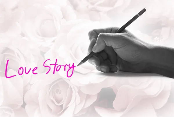 Χέρι κρατώντας ένα μολύβι σε ένα vintage τριαντάφυλλο φόντο, γράφοντας για τη λέξη "ιστορία αγάπης " — Φωτογραφία Αρχείου