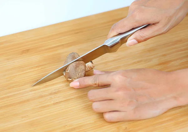 Scharfes Messer an Frauenhänden zerschnitt Shiitake-Pilz auf Holzblock — Stockfoto