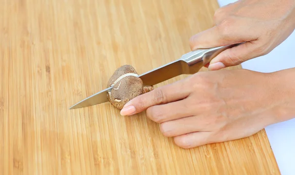 Scharfes Messer an Frauenhänden zerschnitt Shiitake-Pilz auf Holzblock — Stockfoto
