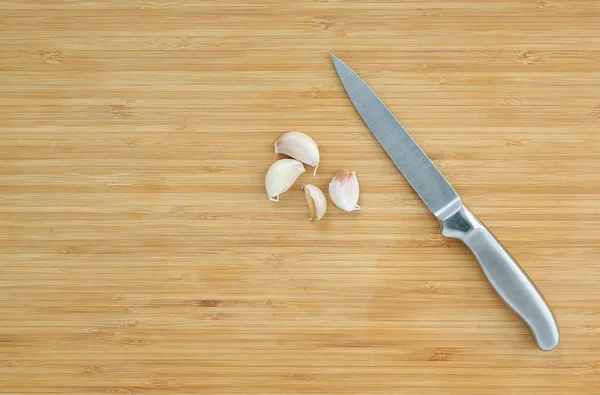 Scharfes Messer und Knoblauch auf Holzblock — Stockfoto
