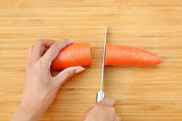 Woman cutting Carrot for cooking on wood block — Stock Photo, Image