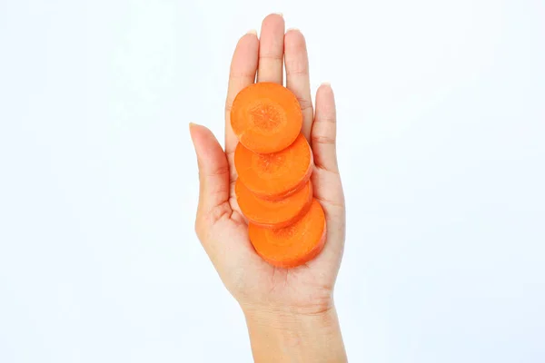 Fetta di carota nella mano della donna su sfondo bianco — Foto Stock