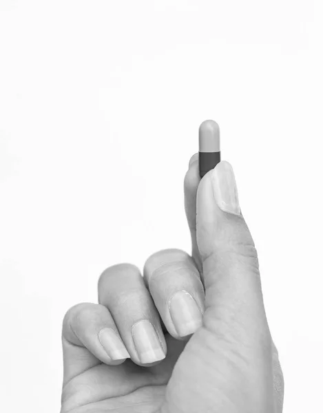Finger hält Pille auf weißem Hintergrund, Schwarz-Weiß-Ton — Stockfoto