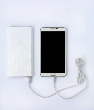 Beyaz arka planda güç bankasıyla şarj olan akıllı telefon