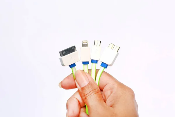 Manos que sostienen muchos adaptadores de tipo en 1 cargador USB sobre fondo blanco. cargador universal —  Fotos de Stock