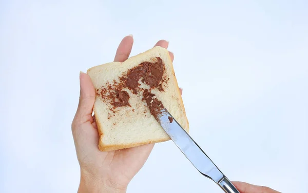 Mão segurando pão e geléia de chocolate para o café da manhã no fundo branco — Fotografia de Stock