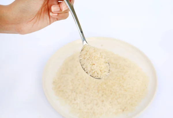 Tenendo in mano riso gelsomino su cucchiaio su sfondo bianco . — Foto Stock