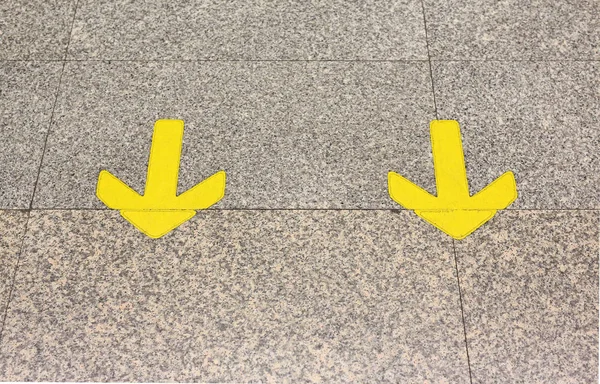 Segno freccia gialla indicano sul pavimento di marmo — Foto Stock