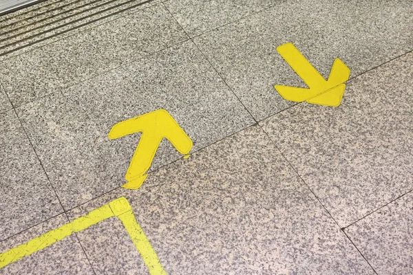 黄色箭头标志，以表示在大理石地板上 — 图库照片