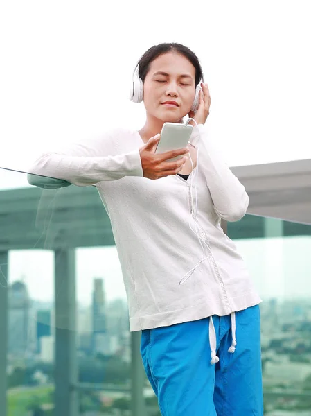 Jeune femme asiatique écouter de la musique dans les écouteurs sur le toit du bâtiment . — Photo