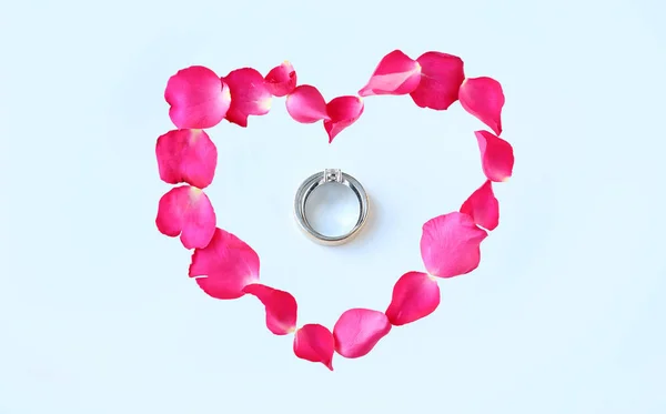 白い背景で隔離のカップルの結婚指輪とハートの形にバラの花の花弁. — ストック写真