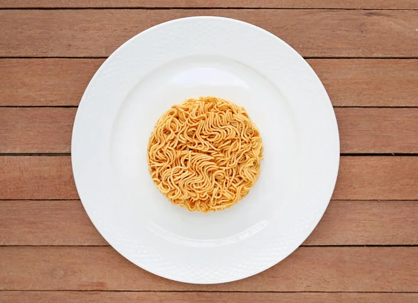 Instant noodles in white circle plate against wooden plank. — Stock Photo, Image