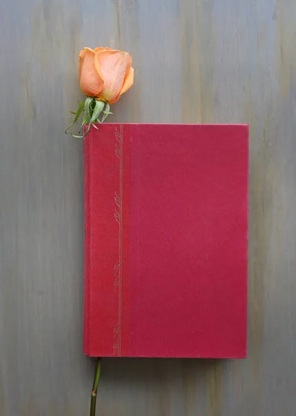 Rose flower and red hardcover on wooden background. — Stock Photo, Image