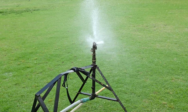 Sprinkler watering the grass in the green field. — Stock Photo, Image