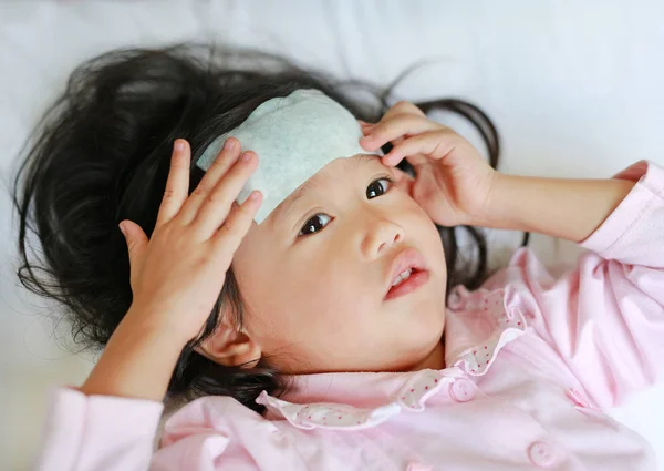 Ragazza malata sdraiata sul letto con una gelatina fresca sulla testa . — Foto Stock