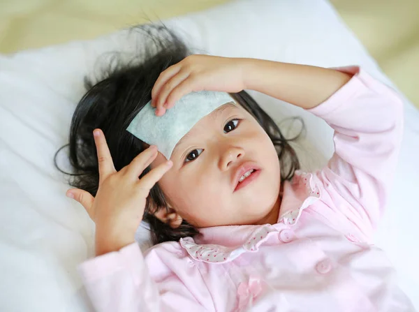 Ragazza malata sdraiata sul letto con una gelatina fresca sulla testa . — Foto Stock