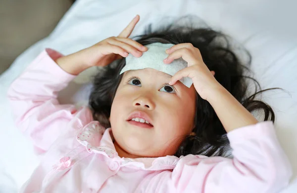 Niña enferma acostada en la cama con una gelatina fría en la cabeza . —  Fotos de Stock