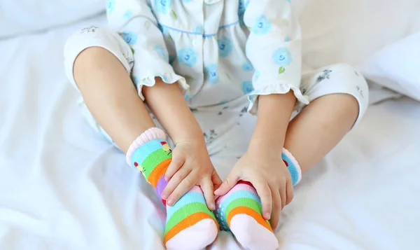 Gadis kecil yang manis mencoba untuk menempatkan kaus kaki di tempat tidur . — Stok Foto