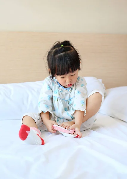 Urocza dziewczynka próbuje umieścić skarpety na łóżku. — Zdjęcie stockowe