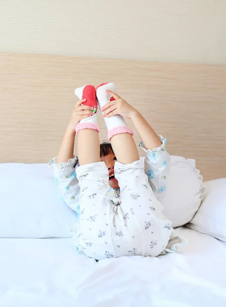 Adorable little girl trying to put a socks on the bed. — Stock Photo, Image