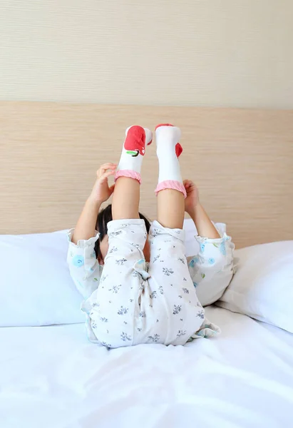 Adorable little girl trying to put a socks on the bed. — Stock Photo, Image