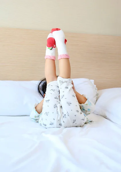 Adorable little girl trying to put a socks on the bed. — Stock Photo, Image