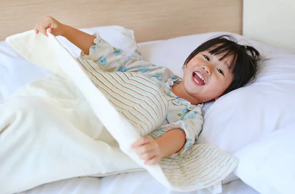 Αστείο, μικρό κορίτσι, ξαπλωμένη στο κρεβάτι με την κουβέρτα. — Φωτογραφία Αρχείου