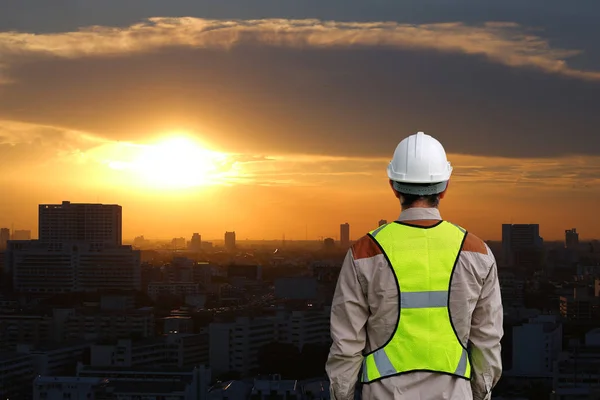 Vista trasera del trabajador de la construcción masculino contra la construcción al atardecer en el fondo de la ciudad de Bangkok — Foto de Stock